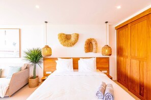 Ein Schlafzimmer mit einem Holzkopfteil, weißer Bettwäsche, einem Blumentopf und einem großen Holzschrank.