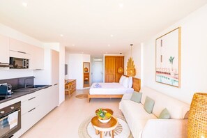 A modern hotel room with a kitchenette, a bed, a sofa, a dining table, and a view of a pool. - DDL 624, sea view, beach front, serenity and comfort (Anse Marcel)