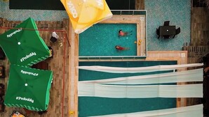 An aerial view of a swimming pool area with multiple umbrellas, a pool, and lounge chairs. - Batu pansiyon (Kumluca)