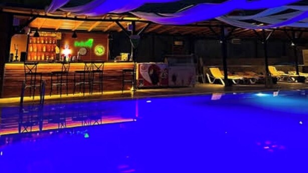 A pool area with a bar and lounge chairs under a canopy. - Batu pansiyon (Kumluca)
