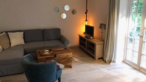 Ein Wohnzimmer mit einer Couch, einem Couchtisch, einem Fernseher und einer Lampe.
