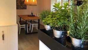 Ein Essbereich mit Holztisch und Stühlen, einer Pendelleuchte und Topfpflanzen.
