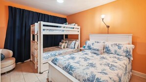 A room with a bunk bed, a bedside table, a lamp, and a chair. - Jade East 130- Jade Gem (Destin)