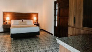 A hotel room with a bed, two bedside lamps, a wooden headboard, a patterned carpet, and a wooden wardrobe. - catleya royal club (Pereira)