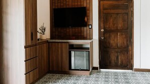 A compact kitchen with a built-in TV, wooden cabinets, a small refrigerator, and a patterned floor. - catleya royal club (Pereira)