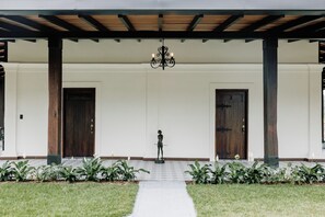 Un acceso cubierto con dos puertas de madera, una estatua y un sendero que conduce a las puertas.