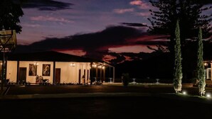 A building with a well-lit entrance, a clear sky, and a crescent moon. - catleya royal club (Pereira)