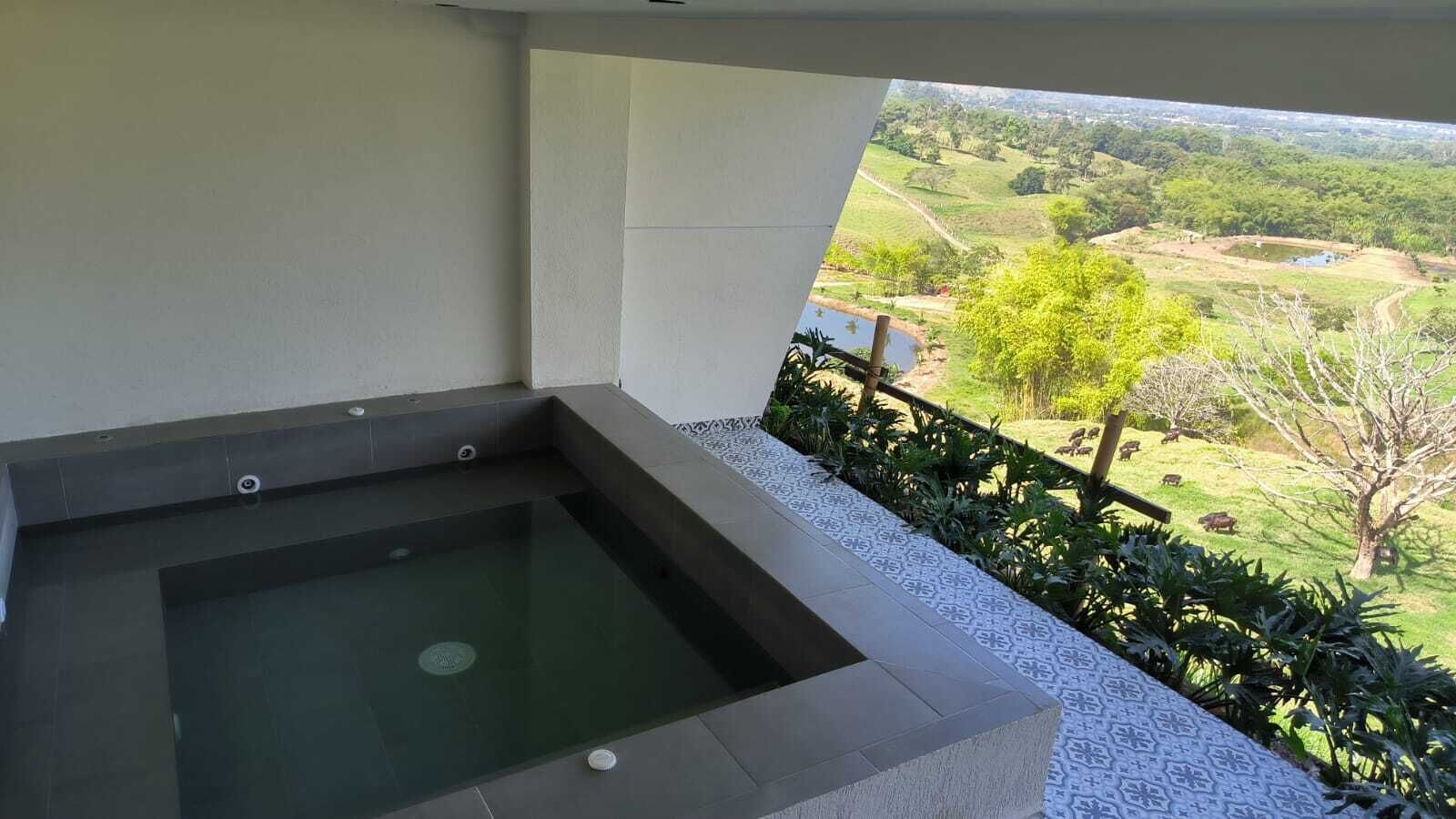 A hot tub on a balcony with a view of a green landscape.