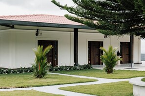 A building with a red-tiled roof, a front porch, and a pathway leading to the entrance. - catleya royal club (Pereira)