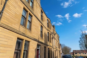 A multi-story building with a brick facade, multiple windows, and a clear blue sky. - Falkirk Urban Apartment - Free Parking (Falkirk)