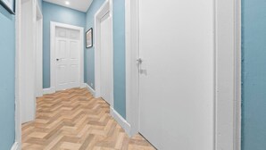 Un couloir avec un plancher en bois, des portes blanches et des murs bleus.