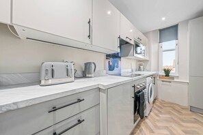 A modern kitchen with white cabinets, a built-in microwave, a toaster, and a kettle. - Falkirk Urban Apartment - Free Parking (Falkirk)