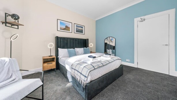 Ein Schlafzimmer mit einem Bett, Nachttischen, einem Spiegel und einer Tür.