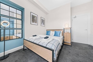 A bedroom with a bed, a bedside table, a wardrobe, and a window with a view of a waterfall. - Falkirk Urban Apartment - Free Parking (Falkirk)