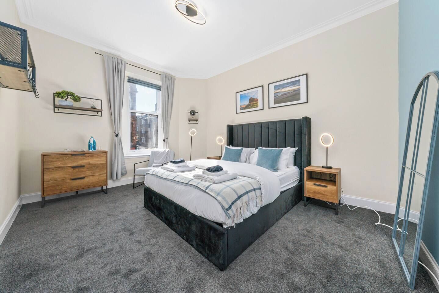 Une chambre moderne avec un grand lit, des tables de chevet, une commode et une fenêtre avec des rideaux.