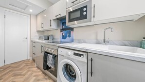 Une cuisine moderne équipée d’un lave-linge intégré, d’un four à micro-ondes et d’un évier.