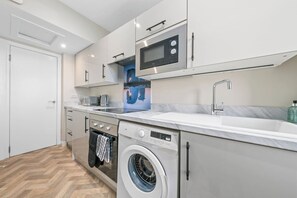 Une cuisine moderne équipée d’un lave-linge intégré, d’un four à micro-ondes et d’un évier.