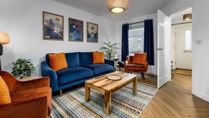 A living room with a sofa, armchair, coffee table, and a hanging light fixture. - Modern 2-Bed Stirling House | Driveway Parking (Stirling)