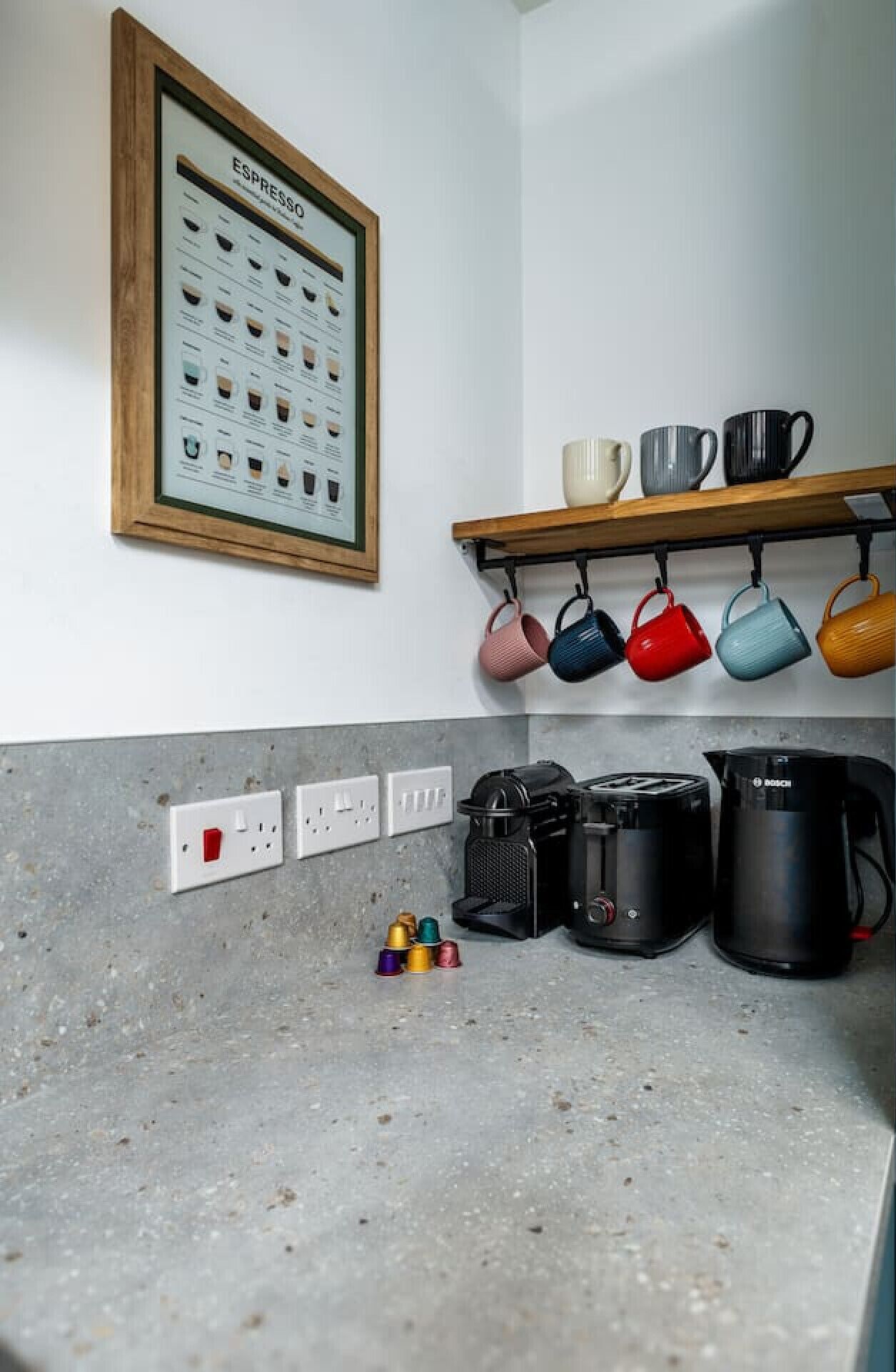 A kitchen with a coffee machine, a toaster, and a kettle on the counter.