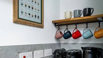 A kitchen with a coffee machine, a toaster, and a kettle on the counter.