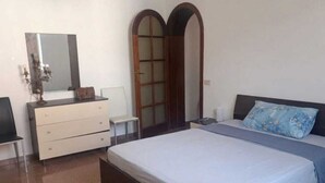 A bedroom with a bed, dresser, mirror, and a sliding door. - Casa Fedafa  (Parghelia)