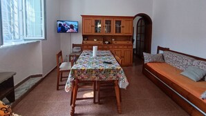 A dining area with a table, chairs, a sofa, a television, and a wooden cabinet. - Casa Fedafa  (Parghelia)