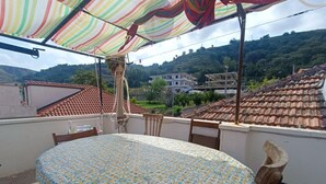 A round table with a patterned tablecloth, a wooden chair, and a colorful striped awning. - Casa Fedafa  (Parghelia)