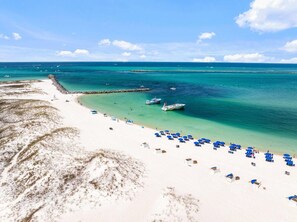 Ein Strand mit weißem Sand, klarem türkisblauem Wasser und ein paar Booten.