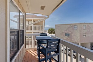 Ein Balkon mit Tisch und Stühlen, Blick aufs Meer, und ein Gebäude mit Balkon.