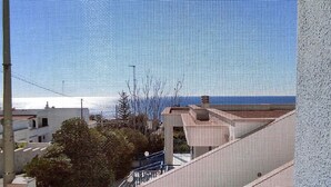 Ein Balkon mit Meerblick, Fliesenboden und einer weißen Wand.