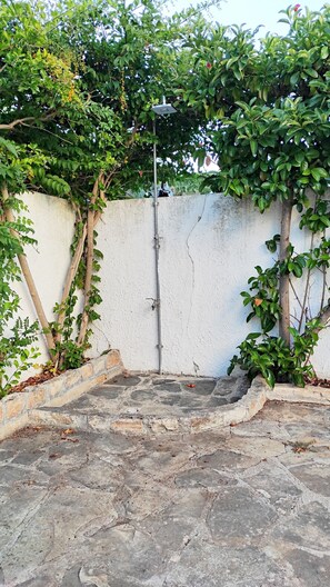 Ein Innenhof mit weißer Mauer, einem Metallpfosten und einem Steinboden.