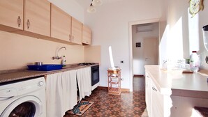 Una cocina con lavadora, lavamanos, armarios y estufa.