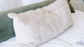 A bed with white bedding and a green pillow.