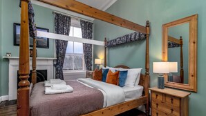 A four-poster bed with a wooden frame, a bedside table with a lamp, and a mirror on the wall. - The Cosy Nook - Free Parking Nearby (Dunblane)