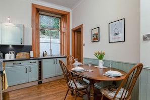 Un comedor con una mesa de madera, sillas y una ventana con vistas a zonas verdes.