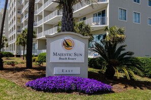 Schild für das Majestic Sun Beach Resort mit einer Palme und violetten Blüten im Vordergrund.