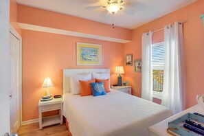 A bedroom with a bed, two bedside tables, a ceiling fan, a window with curtains, and artwork on the walls. - Majestic Sun 711b- 7th Heaven (Miramar Beach)