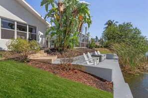 Ein modernes Haus mit Terrasse, einem kleinen Garten und einem Teich.