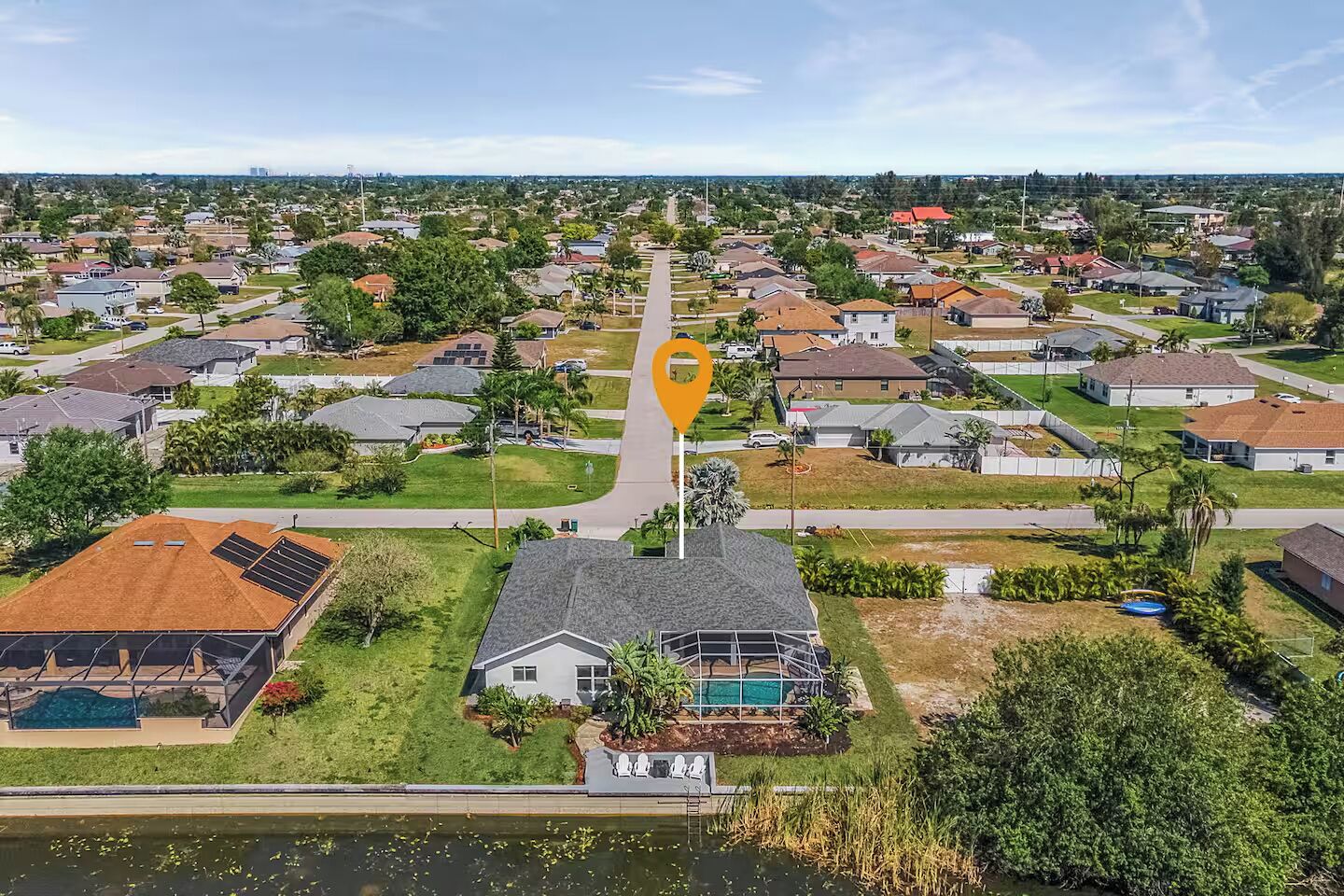 Ett flygbildsbild av ett bostadsområde med hus, en swimmingpool och solpaneler.
