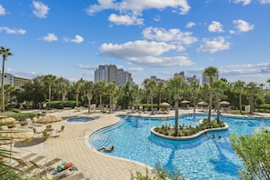 Ein Resort-Poolbereich mit mehreren Schwimmbecken, Liegestühlen und Palmen.