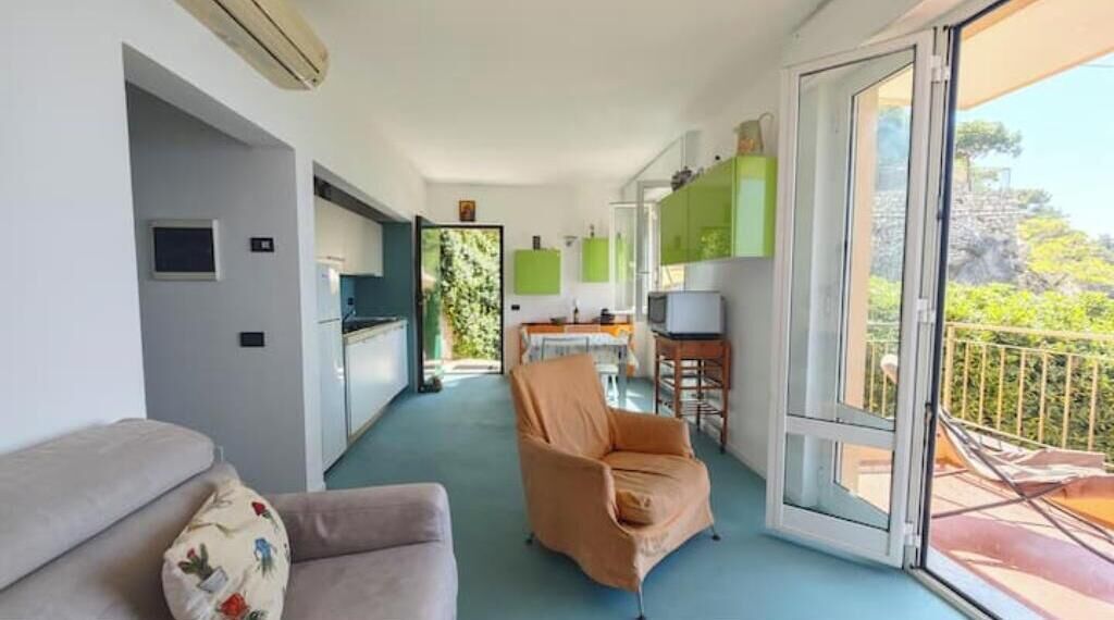 A modern interior with a sofa, armchair, and a balcony with a railing.