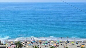 Uma praia com pessoas, guarda-sóis e o oceano.