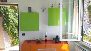 Quarto com porta de vidro, uma escrivaninha vermelha com uma tigela, uma luminária e uma pequena estátua.
