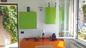 Une pièce avec une porte vitrée, un bureau rouge sur lequel se trouve un bol, une lampe et une petite statue.