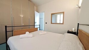 Quarto de hotel com cama, mesa de cabeceira, espelho e guarda-roupa.