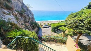 Escadaria que dá para uma praia, com um carro estacionado na estrada.