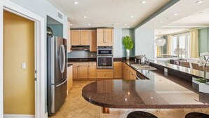 Una cocina moderna con electrodomésticos integrados, encimera de granito y comedor con vistas.