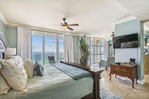 Ein Schlafzimmer mit Bett, Deckenventilator, Fernseher, Pflanze und Meerblick.