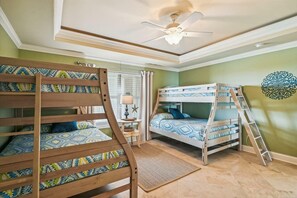 Ein Zimmer mit Etagenbetten, Deckenventilator, einem fenster mit Vorhängen und einem Wandbild.