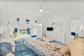 A bedroom with bunk beds, a desk, a dresser, a TV, and a window with a view. - Majestic Sun 312b - 3 Tortugas (Miramar Beach)